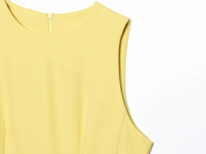 Détail du col d'une robe jaune sans manches avec tissu texturé et fermeture éclair invisible