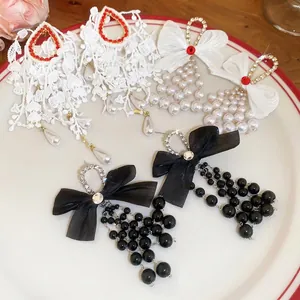 Vintage style bow earrings with pearls and red crystals on white ceramic plate