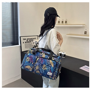 Blue travel bag with tropical leaf print and adjustable strap shown on model
