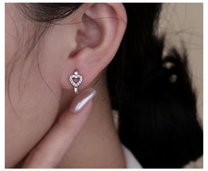 Close-up of S925 silver heart hoop earrings with sparkling cubic zirconia on ear