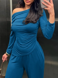 Detail of blue long-sleeved off-shoulder top with pleated texture and matching trousers