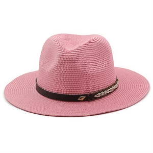 Detail of pink woven straw hat featuring a leather band and decorative metal buckle