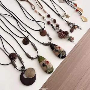 Detailed shot of ethnic long necklaces with wooden rings, feathers, and tassels on wax cords