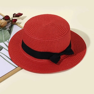 Close-up of red boater hat with black ribbon bow on a stylish vintage background