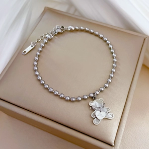 Detailed macro of silver bear charm and heart pendant on a 316 steel beaded bracelet