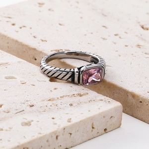 Macro shot of silver cable texture ring featuring a bezel-set pink rectangular gemstone