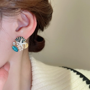 Macro shot of gold-plated starfish and shell earrings featuring blue pearls and rhinestones