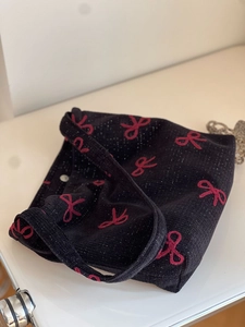 Detail of red bow embroidery on black corduroy canvas shoulder bag with secure buckle
