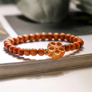 Nahaufnahme von Ebenholz Armband mit geschnitztem Blumenanhänger und Goldperlen