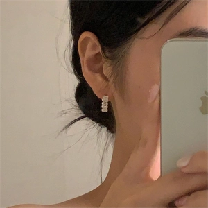 Minimalist rectangular gold hoop earrings with zircon stones worn by a model