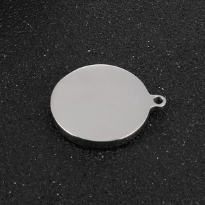 Macro shot of silver circular stainless steel pendant on textured black background