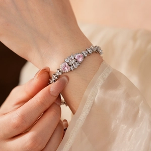 Close-up of a silver flower bracelet with pink heart-shaped zircons on a model's wrist