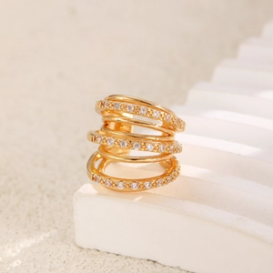 Macro shot of gold layered ring with rows of clear zircon stones on a white stand