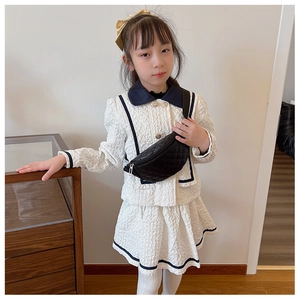 Detail of children's cream textured outfit with navy collar and black quilted waist bag