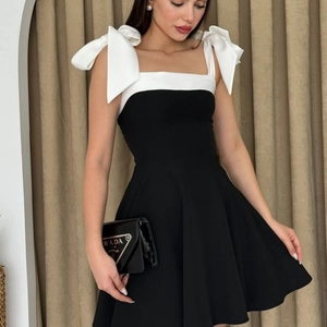 Elegant black and white A-line dress featuring large white bow straps and off-shoulder cut