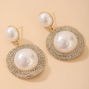 Macro detail of luxury geometric gold earring with white pearls and sparkling rhinestones