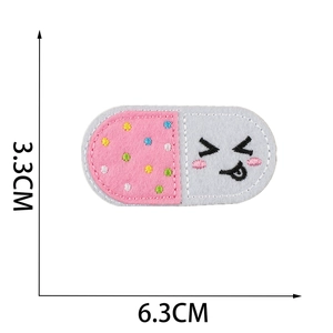 Pill shaped capsule embroidery patch with cute face emoji and dimensions 6.3cm x 3.3cm