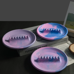 Détail d'un cendrier rond avec texture de marbre rose, bleu et violet sur des livres
