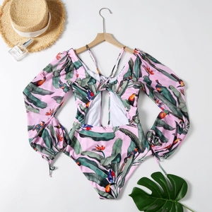 Dettaglio flat lay del costume a maniche lunghe con stampa tropicale su base rosa