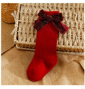 Detail of red ribbed cotton baby knee-high socks with a large sequin bow accent