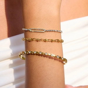 Three-piece gold-tone bracelet set with zircons shown on wrist against white fabric