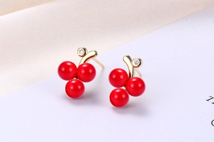 Macro shot of s925 silver cherry earrings with red fruit and gold stem zircon details