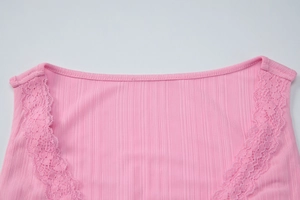 Dettaglio del tessuto in cotone a coste rosa con bordo in pizzo sullo scollo a V