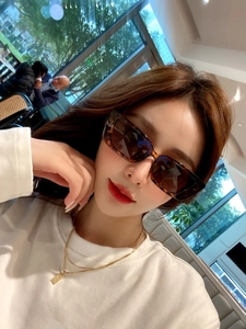 Detail of tortoise shell rectangular sunglasses with a golden layered chain necklace