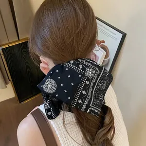 Chouchou rétro en mousseline noire avec imprimé paisley blanc sur une queue de cheval