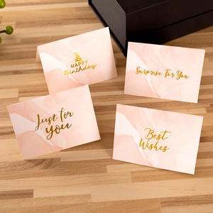 Pink marble greeting cards with gold foil lettering including Happy Birthday on wood