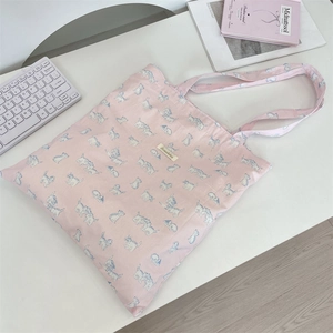 Detail of pink canvas tote bag with blue cat prints and a stitched brand label on top