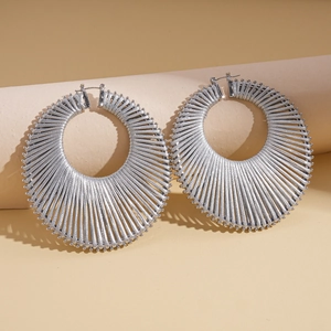 Detail showing oversized silver geometric hoop earrings with radiant woven texture