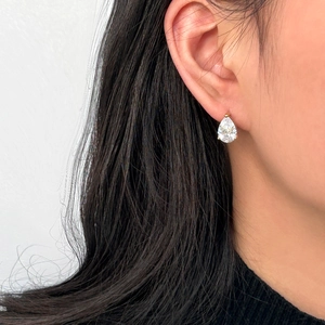 Macro shot of a pear-shaped emerald green zircon earring with a gold claw setting