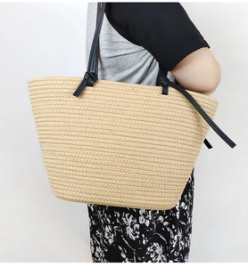 Detail of beige woven cotton rope tote bag with black leather shoulder straps and knotted knots