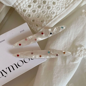 Detailed macro view of white marble acetate hair clips with vibrant colored rhinestones