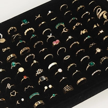 Detailed close-up of 16-piece gold earring and ring set displayed on black velvet box