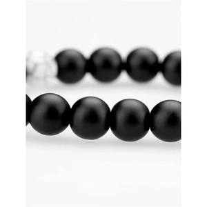 Macro view of matte black agate beads with one white marble accent bead on bracelet