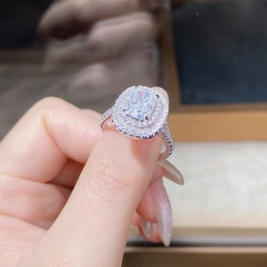 Macro shot of 4-carat cushion-cut moissanite ring with double halo pavé setting on finger
