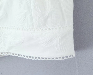 Détail de la broderie blanche et de l'ourlet en dentelle ajourée sur le haut et la jupe