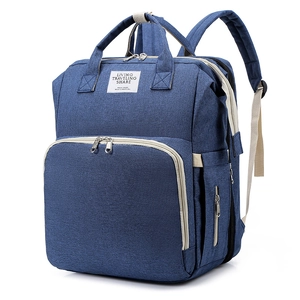 Close-up of deep blue multifunctional diaper bag with reinforced handles and travel label