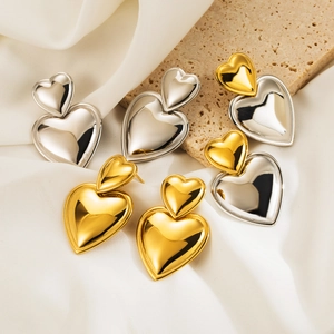 Detail of double heart dangling earrings in gold and silver finish on stone base