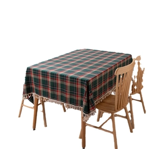 Red and green plaid Christmas tablecloth with cream tassels on a rectangular dining table