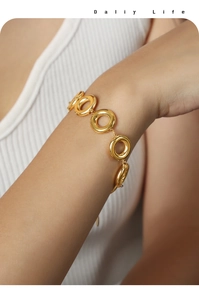Close-up of 18k gold geometric circle chain bracelet worn on a female wrist