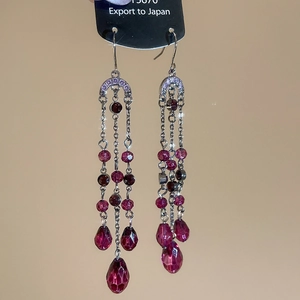 Détail de boucles d'oreilles à pompons en cristal argenté avec perles violettes et magenta