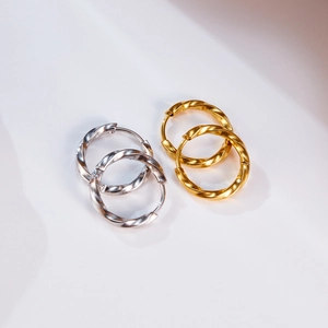 Detail showing gold and silver mobius twist hoop earrings with textured finish