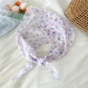 Detailed view of a purple silk scarf with butterfly floral print tied in a knot style
