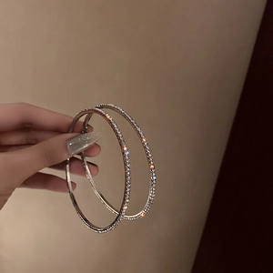Silberne Creolen mit funkelnden Kristallen in einer handgehaltenen Darstellung