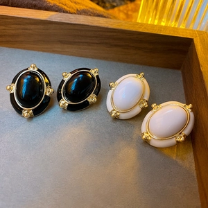 Detail view of vintage oval enamel earrings in black and white on a wooden tray