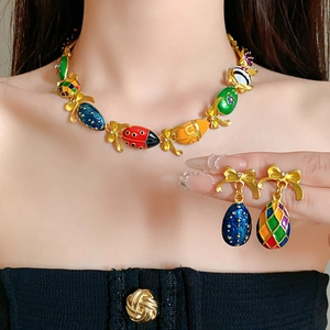 Detail of vintage enamel egg pendant necklace and earrings set with gold bow design