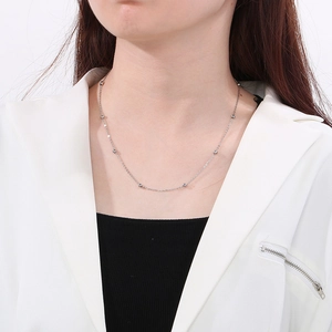 Detail of silver titanium bead necklace on model featuring a minimalist cable chain design